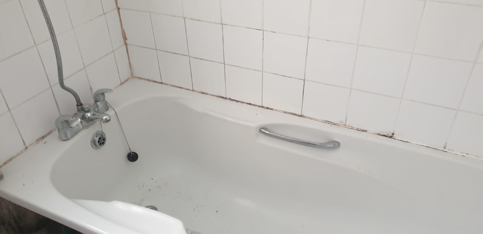 Bath with mouldy failed sealant before